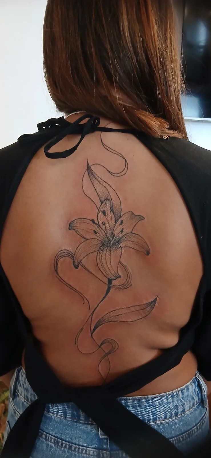 Tatuagem floral autoral seguindo a linha das costas.