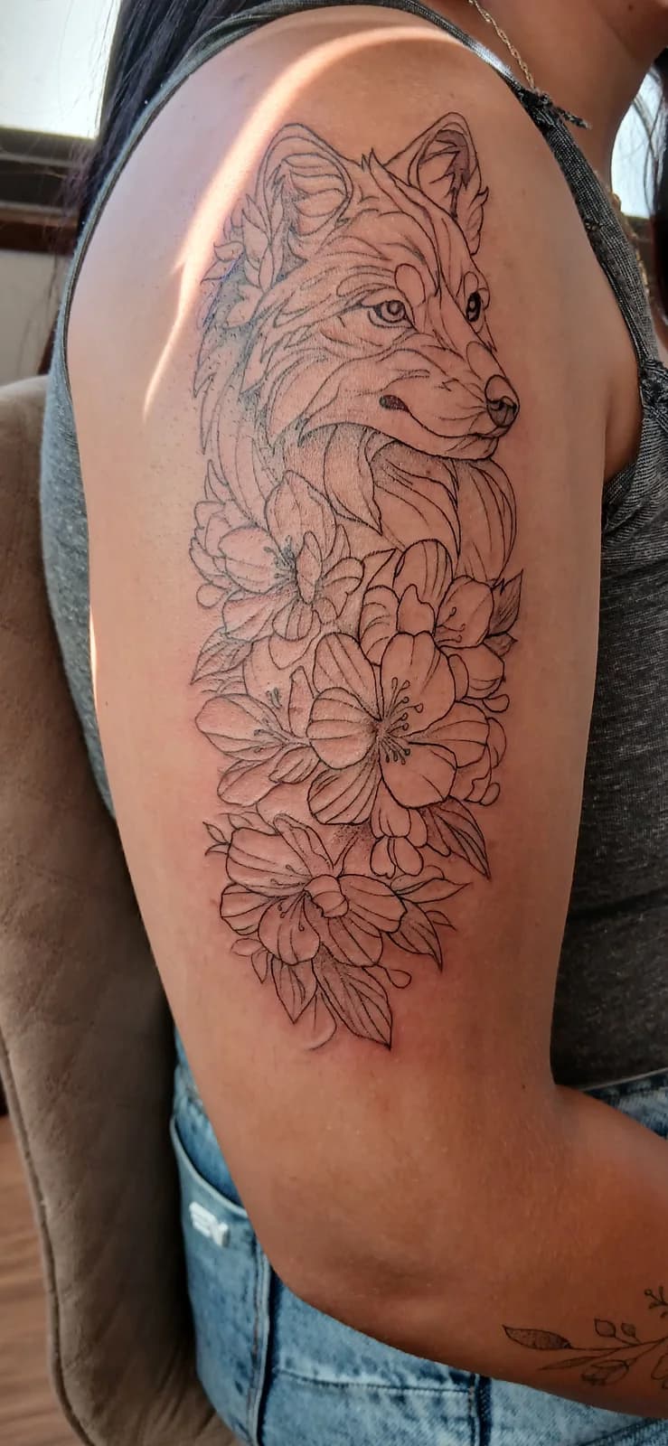 Tatuagem floral em composição vertical no braço.