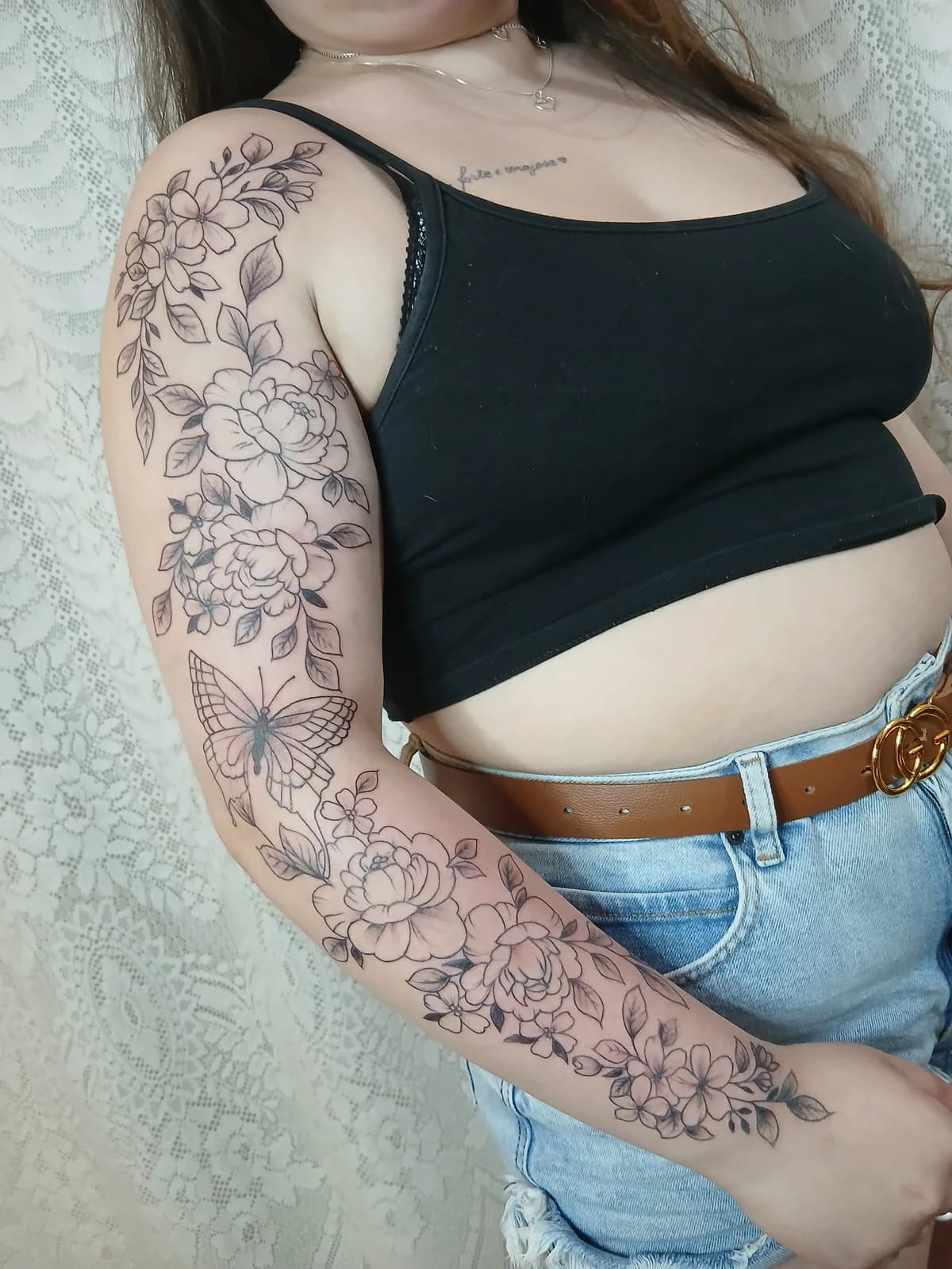 Tatuagem floral em composição de manga no braço.