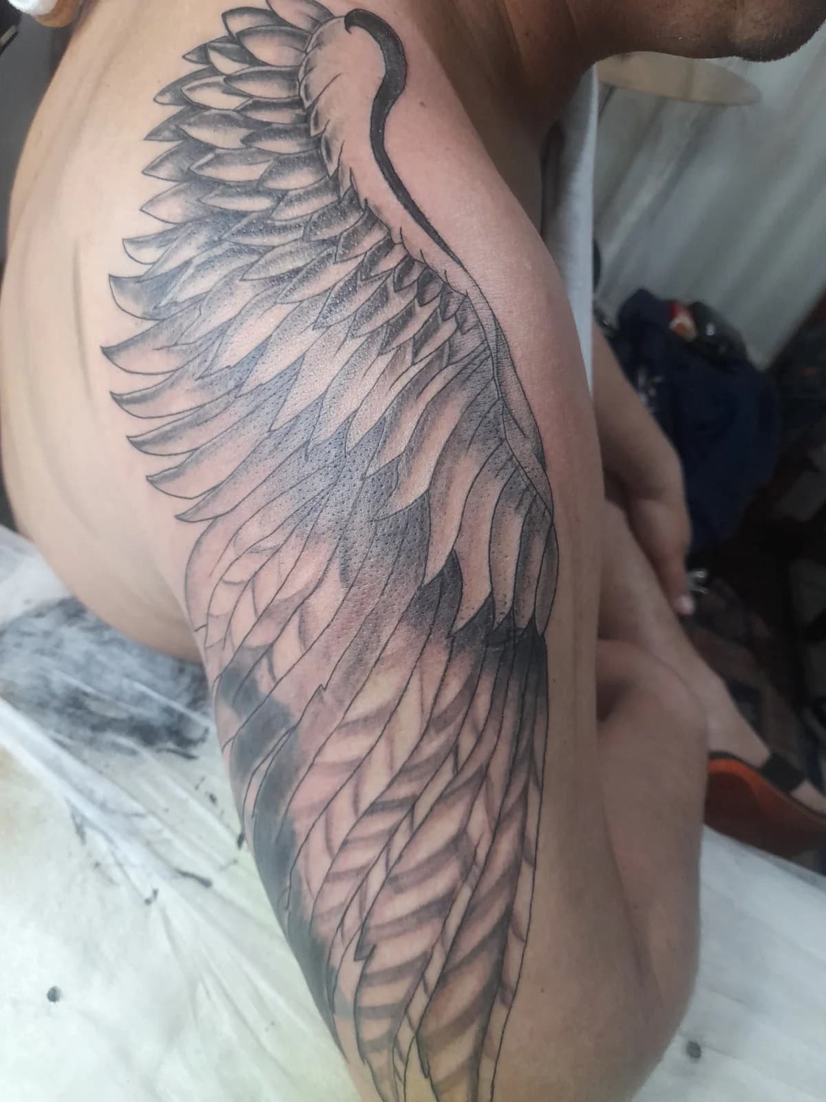 Tatuagem de asa ornamental em preto.